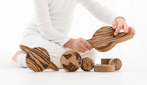 Child kneeling down, holding handmade wooden planets during play.