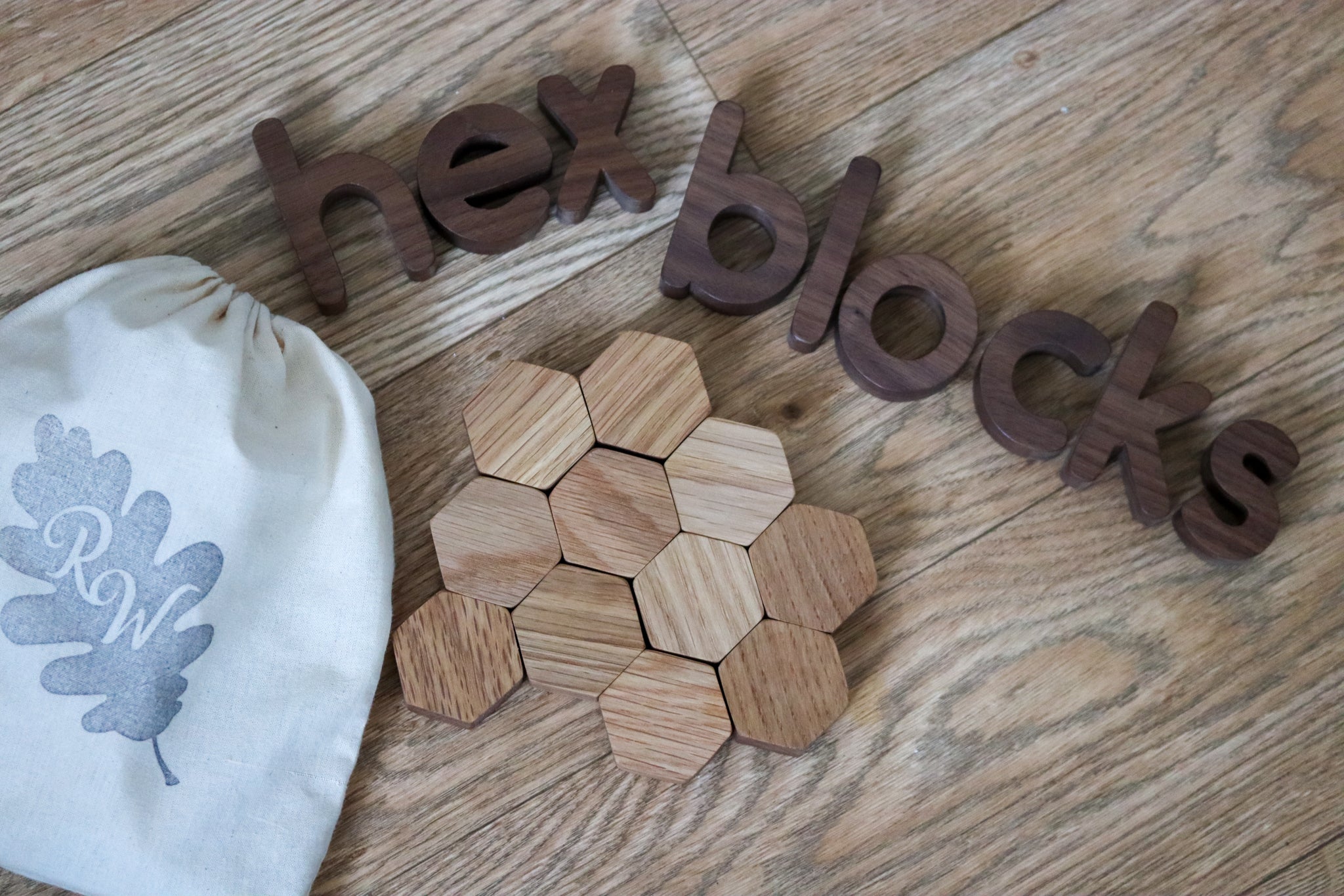 Wooden oak small hexagon blocks tipped out of a cotton bag onto a wooden floor with the letters hex blocks 