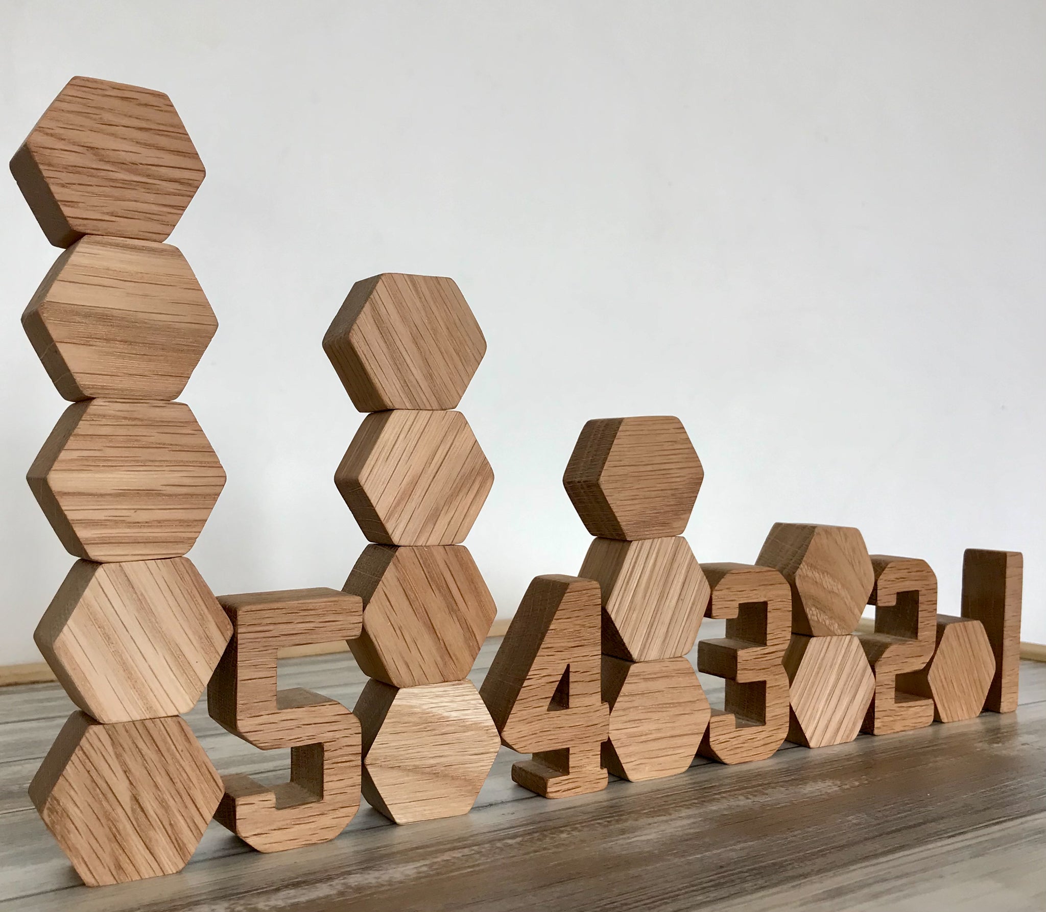 Wooden hexagon block toys stacked on top of each other in towers with wooden numbers next to each tower