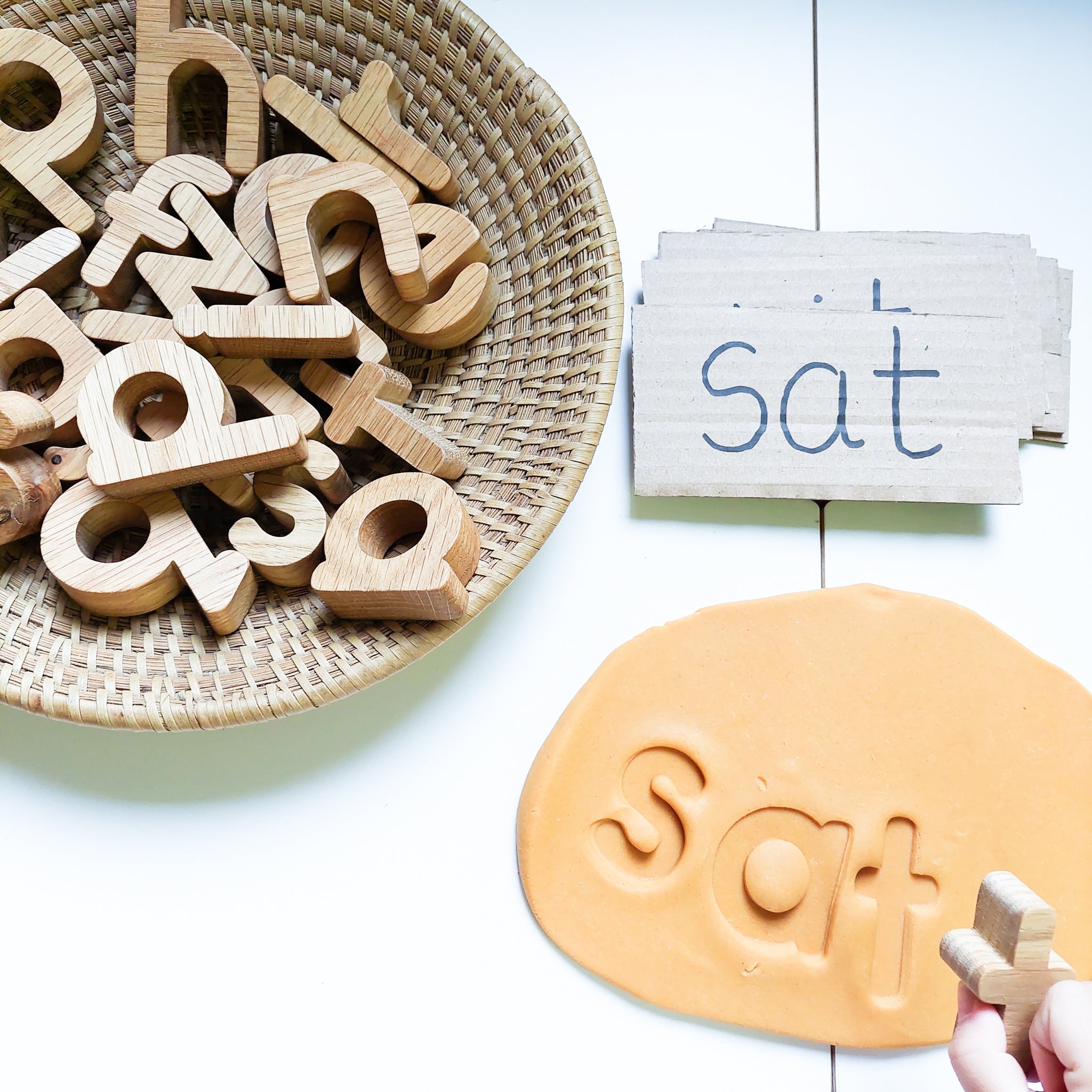 handmade wooden oak alphabet letters toy being used to learn phonics "satpin" whilst being imprinted into playdough.